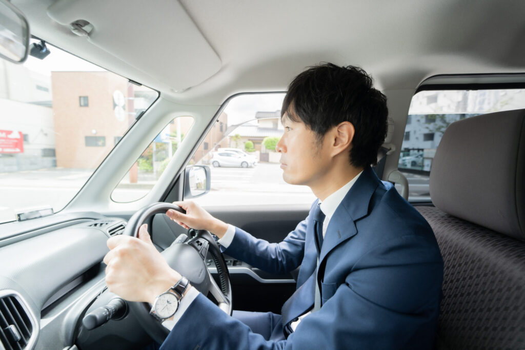 長時間運転で骨盤や腰に負担がかかっている様子の男性(鹿児島まどか整体院ブログ用イメージ)