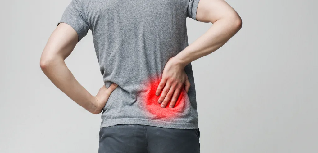 腰の痛みを訴える男性の後ろ姿。赤く強調された腰部が、椎間板ヘルニアや慢性的な腰痛のつらさを象徴しており、鹿児島市の整体院による腰痛ケアの訴求に適したイメージ。