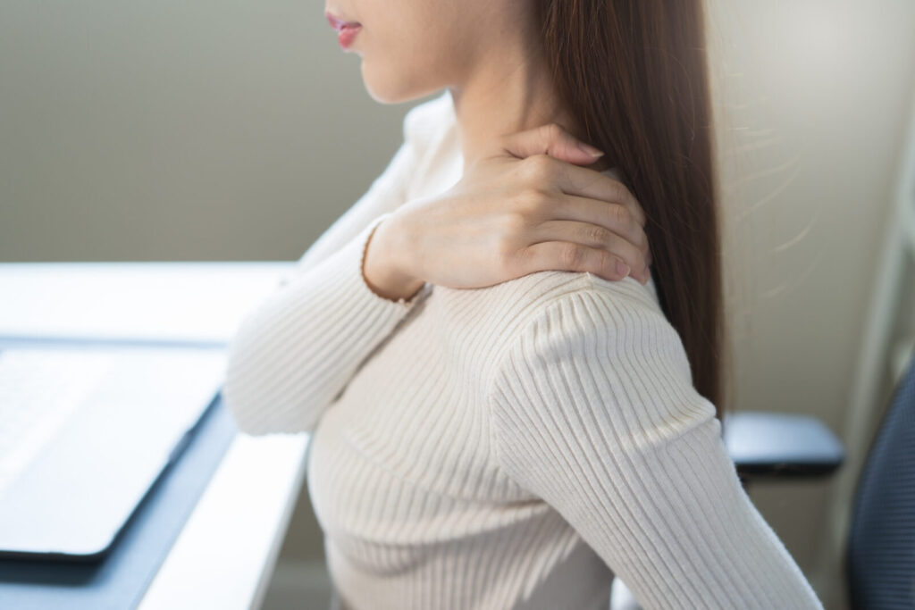 デスクワークで肩こりに悩む女性。姿勢の崩れによる首や肩の負担のイメージ