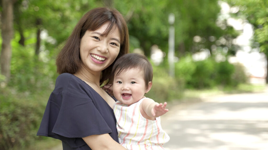 整体で体が軽くなり、笑顔で赤ちゃんを抱く母親。鹿児島市荒田のまどか整体院では、背骨を整えて産後の腰痛を改善し、育児を快適にサポートします。