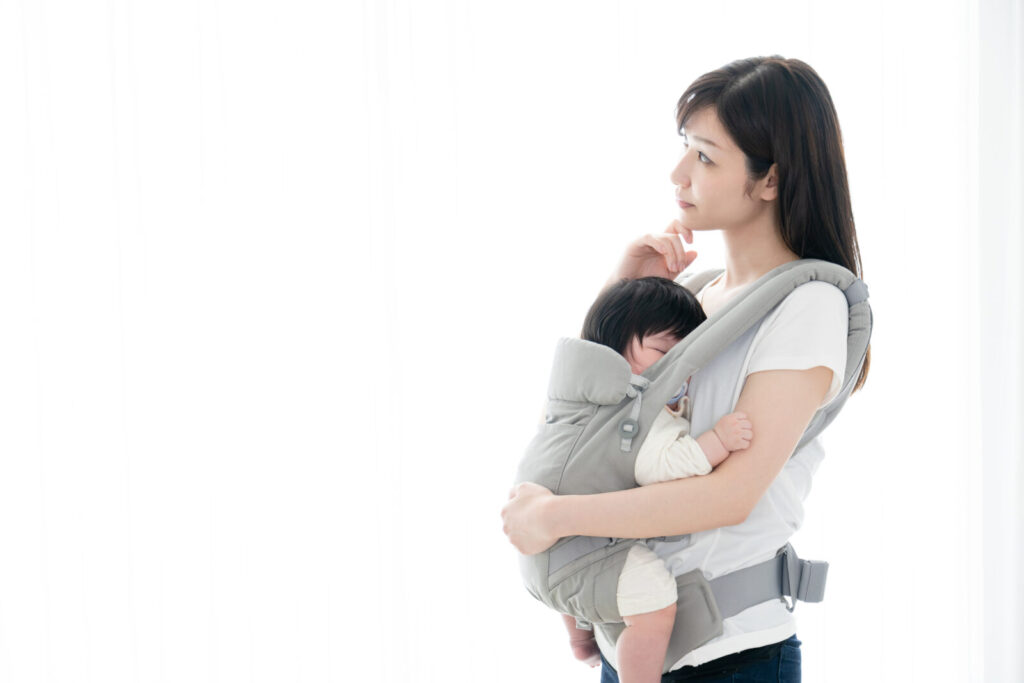 産後の腰痛に悩む母親が赤ちゃんを抱っこしている様子。鹿児島市荒田のまどか整体院では、骨盤よりも背骨ケアを重視し、産後の腰の負担をやさしく整えます。